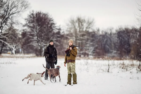Dois caçadores com espingardas em uma floresta nevada de inverno . — Fotografia de Stock