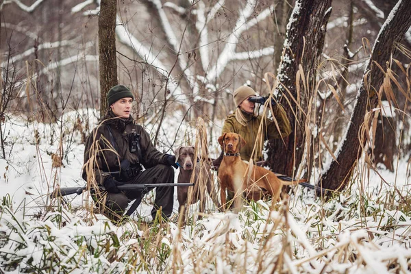 Två jägare med gevär i en snöig vinter skog. — Stockfoto