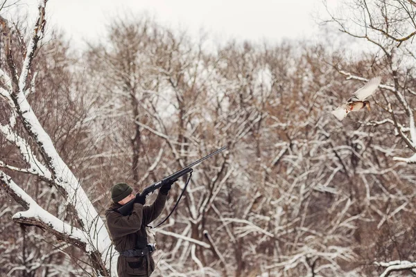 Мужчина-охотник в камуфляже, вооружен винтовкой, стоит в сно — стоковое фото