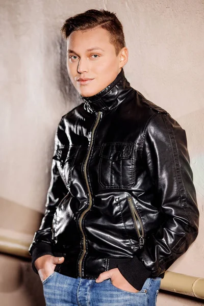 Şık adam duvara yakın ayakta. Şık bir tarzda bir adam