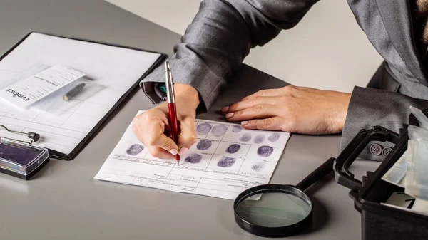 Detective expert writes data into the fingerprint  table — Stock Photo, Image