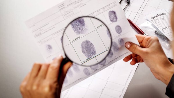 Detective through a magnifying glass looking at a fingerprint 