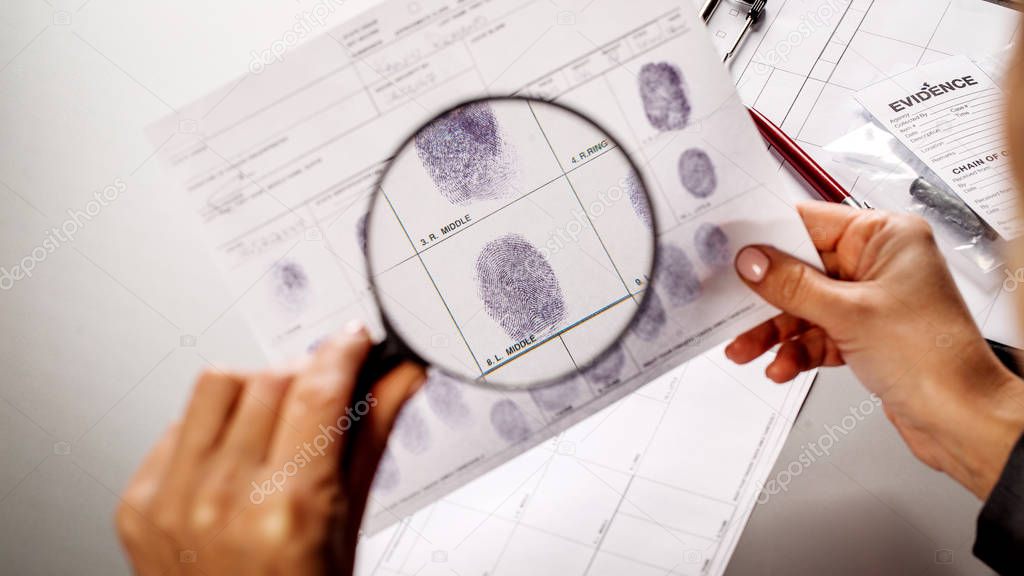Detective through a magnifying glass looking at a fingerprint 