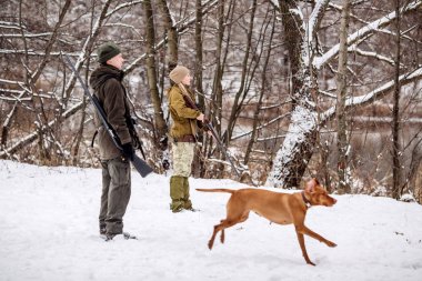 karlı kış orman içinde tüfeklerle iki avcı. 