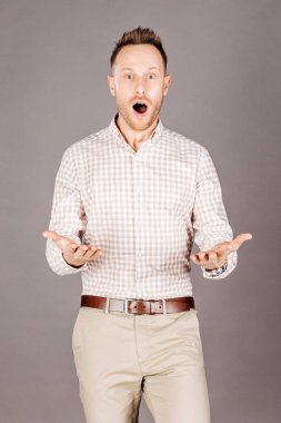 Gri arka plan üzerinde çok şok genç adam. İnsan ifadeleri ve duygular.