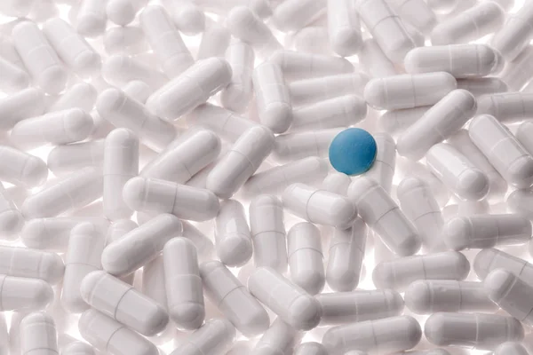 Blauwe capsule onder witte capsules — Stockfoto