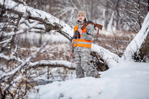 Κυνηγός αρσενικό στο καμουφλάζ, οπλισμένος με ένα τουφέκι, στέκεται σε μια sno — Φωτογραφία Αρχείου