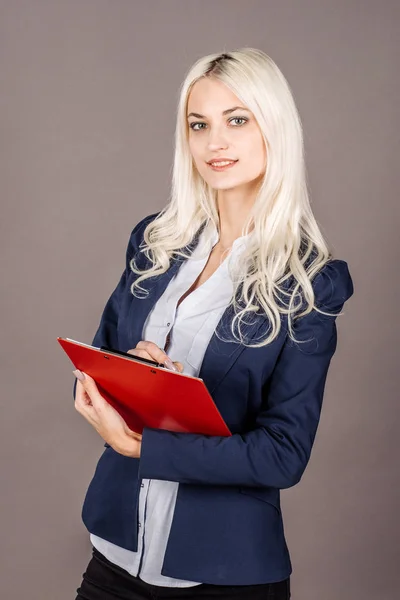 Mujer rubia joven con traje azul escribiendo en el portapapeles. un negocio — Foto de Stock