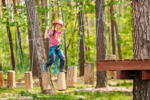 Babymeisje met klimmen vistuig in een avonturenpark bezig zijn ik — Stockfoto