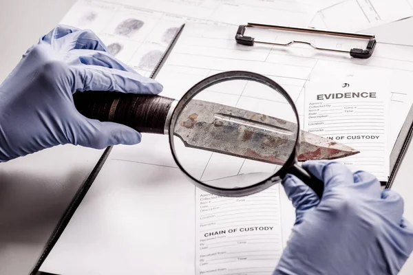 Detective attraverso una lente d'ingrandimento guardando una prova — Foto Stock