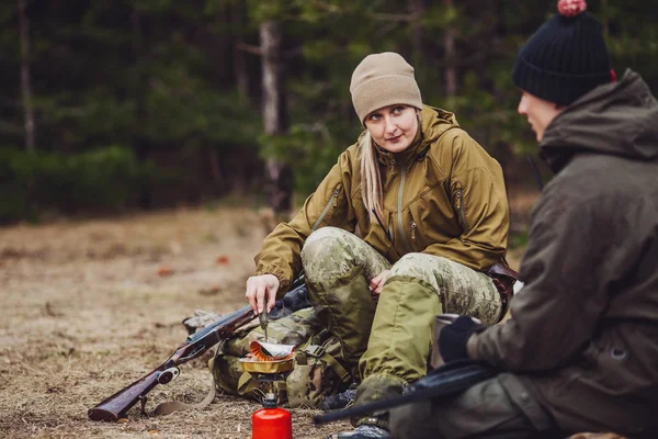Kvinnliga jägare tillaga mat med en bärbar gas-brännare i en vinst — Stockfoto