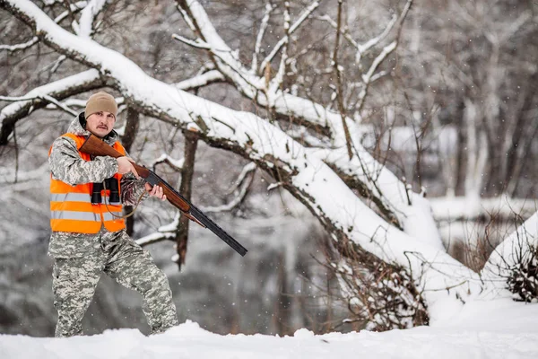 Homme chasseur en camouflage, armé d'un fusil, debout dans une sno — Photo