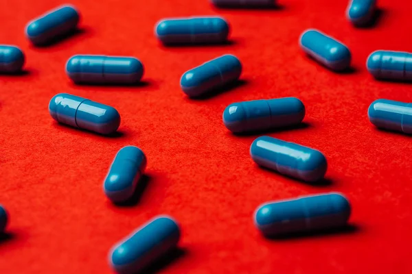 Close up of Blue pills capsule on red background Medicine and pharmacy concept.