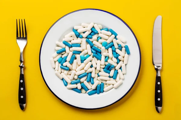 Wiele tabletek na talerzu na żółtym tle. Medycyna i zajmujemy — Zdjęcie stockowe
