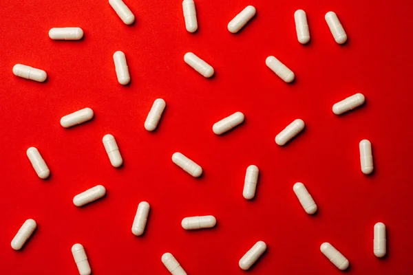 Many white pills on red background. Medicine and pharmacy concep — Stock Photo, Image