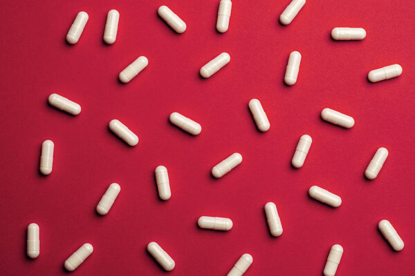 Many white pills on red background. Medicine and pharmacy concep