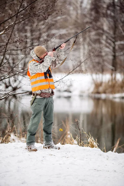 Homme chasseur en camouflage, armé d'un fusil, debout dans une sno — Photo