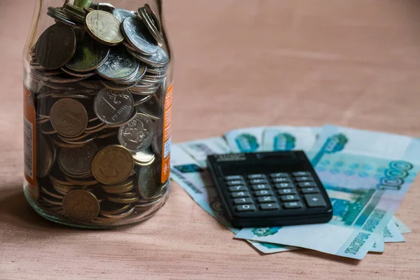 Rus manetleri, hesap makinesi ve ruble dolu cam kavanoz.