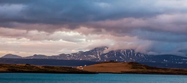 Csodálatos Izlandi természetvédelmi táj. Kilátás a tetején. Magas hegyek, a hó, a hegy riwer és a zöld füves felület. — Stock Fotó