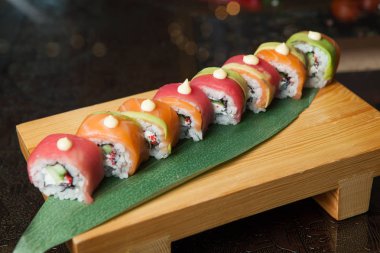 Suşi yemek çeşitli tür siyah arka plan üzerine servis. Plaka üzerinde balık ve pirinç lezzetli taze suşi rulo yakın çekim. Ahşap plaka bir restoranda sunulan suşi rulo