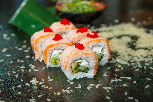 Various kind of sushi food served on black background. Close up of tasty fresh sushi rolls with fish and rice on plate. Sushi rolls served on a wooden plate in a restaurant