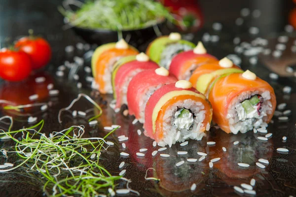 Vários tipos de comida de sushi servida em fundo preto. Close up de saborosos rolos de sushi frescos com peixe e arroz no prato. Rolos de sushi servidos em um prato de madeira em um restaurante — Fotografia de Stock