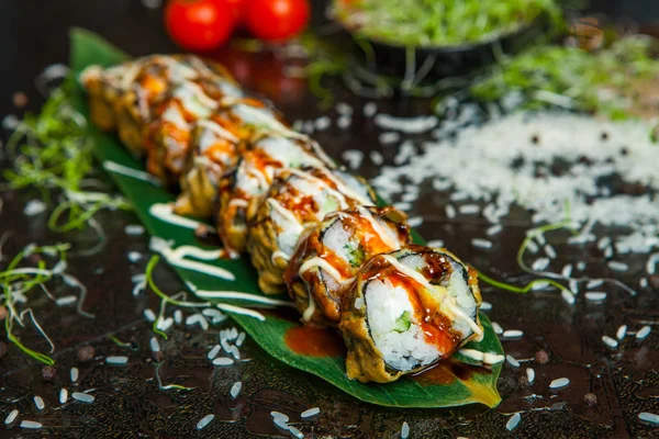 Varios tipos de comida de sushi servida sobre fondo negro. Primer plano de sabrosos rollos de sushi fresco con pescado y arroz en el plato. Rollos de sushi servidos en un plato de madera en un restaurante — Foto de Stock