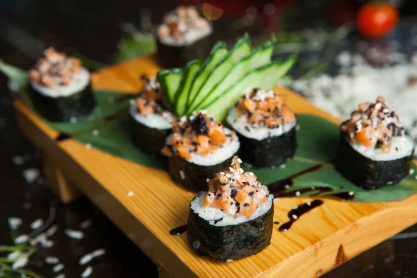 Various kind of sushi food served on black background. Close up of tasty fresh sushi rolls with fish and rice on plate. Sushi rolls served on a wooden plate in a restaurant