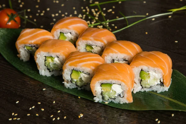 Various kind of sushi food served on black background. Close up of tasty fresh sushi rolls with fish and rice on plate. Sushi rolls served on a wooden plate in a restaurant