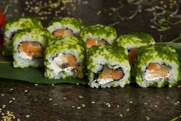 Various kind of sushi food served on black background. Close up of tasty fresh sushi rolls with fish and rice on plate. Sushi rolls served on a wooden plate in a restaurant