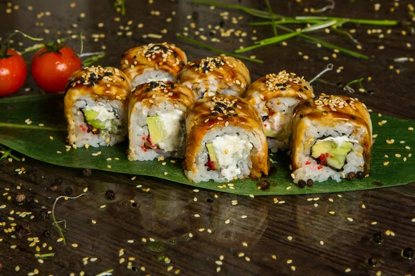 Various kind of sushi food served on black background. Close up of tasty fresh sushi rolls with fish and rice on plate. Sushi rolls served on a wooden plate in a restaurant