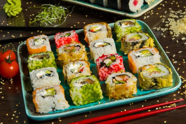 Various kind of sushi food served on black background. Close up of tasty fresh sushi rolls with fish and rice on plate. Sushi rolls served on a wooden plate in a restaurant