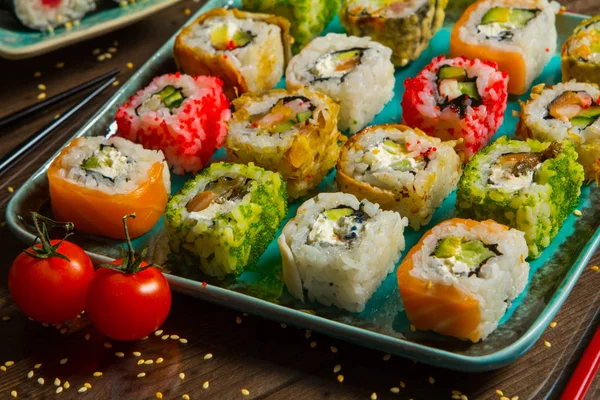 Διάφορα είδη τροφίμων σούσι σερβίρεται σε μαύρο φόντο. Κοντινό πλάνο, νόστιμο φρέσκο σούσι κυλίνδρους με ψάρι και ρύζι στο πιάτο. Σούσι κυλίνδρους σερβίρεται σε ξύλινη πινακίδα σε ένα εστιατόριο — Φωτογραφία Αρχείου