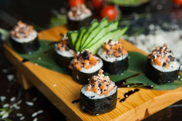 Various kind of sushi food served on black background. Close up of tasty fresh sushi rolls with fish and rice on plate. Sushi rolls served on a wooden plate in a restaurant