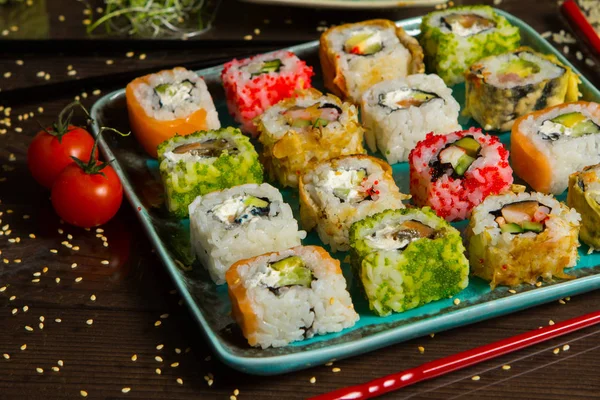 Various kind of sushi food served on black background. Close up of tasty fresh sushi rolls with fish and rice on plate. Sushi rolls served on a wooden plate in a restaurant