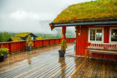Geleneksel Norveç ahşap ev ayakta bir çim ve dağlar içinde belgili tanımlık geçmiş. Tipik Norveç ev. çatı çimen ile tipik Norveç ev.