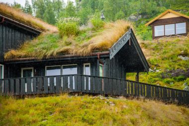 Geleneksel Norveç ahşap ev ayakta bir çim ve dağlar içinde belgili tanımlık geçmiş. Tipik Norveç ev. çatı çimen ile tipik Norveç ev.