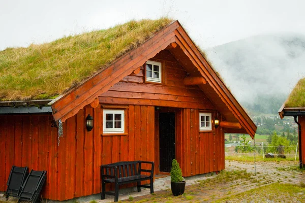 Geleneksel Norveç ahşap ev ayakta bir çim ve dağlar içinde belgili tanımlık geçmiş. Tipik Norveç ev. çatı çimen ile tipik Norveç ev.