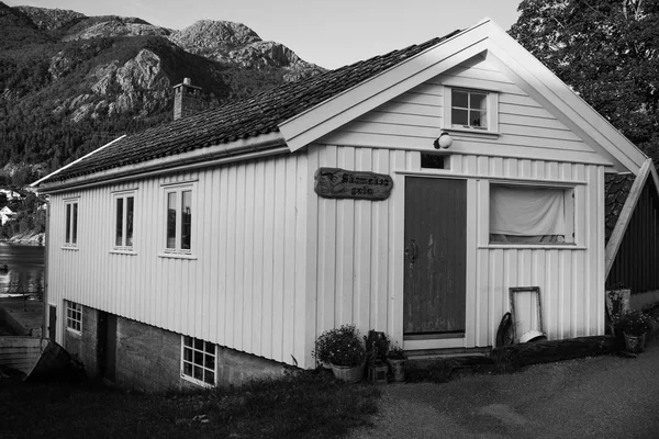Maison traditionnelle en bois nordique debout sur une pelouse et des montagnes en arrière-plan. Typique maison norvégienne. maison typiquement nordique avec de l'herbe sur le toit — Photo