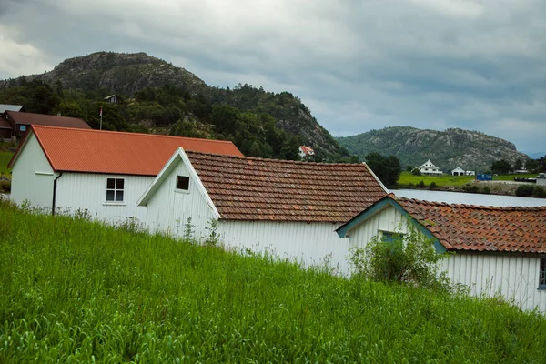 Tradicional casa de madera noruega de pie en un césped y montañas en el fondo. Típica casa noruega. típica casa noruega con césped en el techo — Foto de Stock