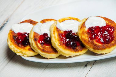 Rus geleneksel syrniki süzme peynir kahvaltı plaka üzerinde krep. Rus cheesecakes beyaz tabakta üzümlü. Peynirli börek