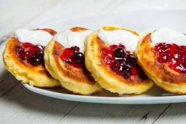 Rus geleneksel syrniki süzme peynir kahvaltı plaka üzerinde krep. Rus cheesecakes beyaz tabakta üzümlü. Peynirli börek