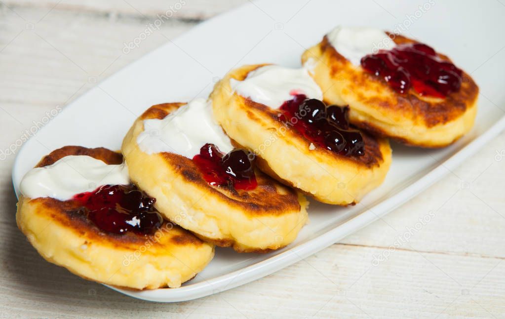 Russian traditional syrniki cottage cheese pancakes breakfast on the plate. Russian cheesecakes with raisins on a white plate. Cheese fritters