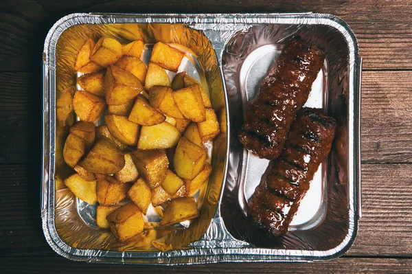 Healthy lunch in aluminum foil package. Top view. Lunch box with food ready to go for work or school. grilled vegetables and chicken meat.