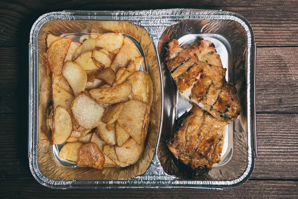 Healthy lunch in aluminum foil package. Top view. Lunch box with food ready to go for work or school. grilled vegetables and chicken meat.