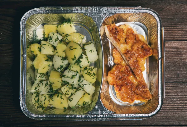 Healthy lunch in aluminum foil package. Top view. Lunch box with food ready to go for work or school. grilled vegetables and chicken meat.