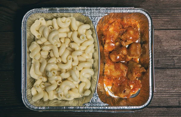 Healthy lunch in aluminum foil package. Top view. Lunch box with food ready to go for work or school. grilled vegetables and chicken meat.