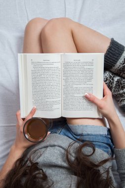 . Yatakta yatan ve bir kitap okuma rahat kadın. 