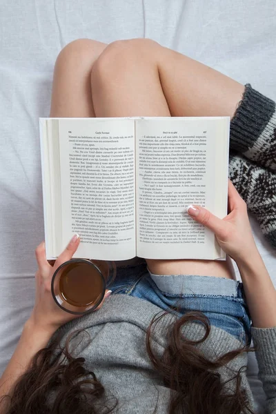 . Yatakta yatan ve bir kitap okuma rahat kadın. 