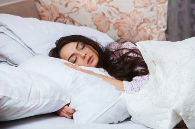 Kız evde beyaz bir yatakta uyuyor. Yatakta evde, üstten görünüm beyaz keten üzerinde pijama içinde uyuyan genç kadın.
